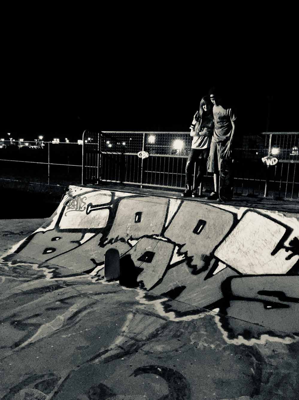 Boy and girl at the top of a short quarterpipe at night