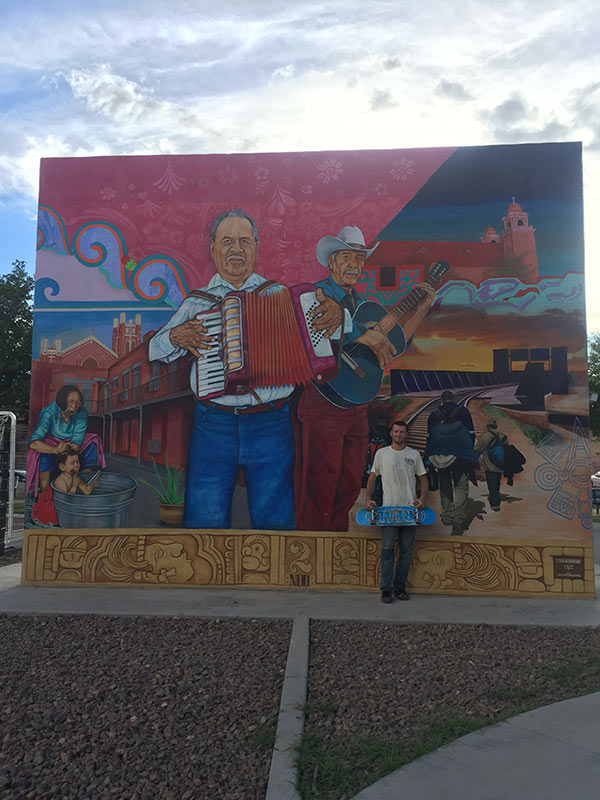 Skateboarder stood against a mural on a wall